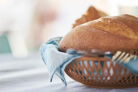 Fresh baked bread loaf served in a small wicker basket on a table Stock Photos