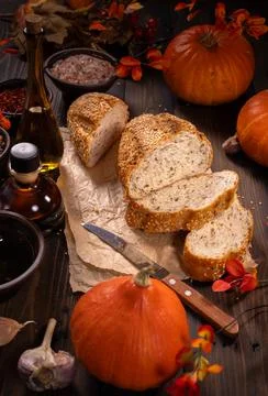 Fresh baked bread, pumpkins, olive oil, and spices on rustic wood Stock Photos