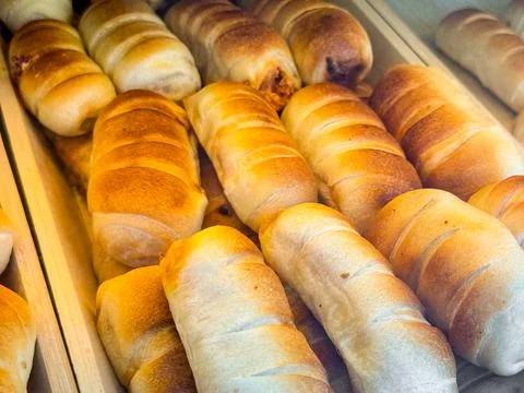 Fresh baked bread rolls arranged on bakery tray with golden crust surface. Fo Stock Photos