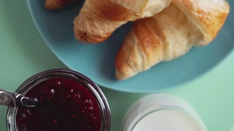 Fresh baked croissants with raspberry jam and milk or yogurt, top view, rotate. Stock Footage 168616079