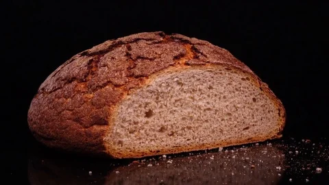 Fresh baked cut round bread with crumbs rotating against black background. 4k Vídeo Stock 73086611
