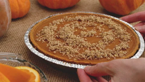 Fresh baked pumpkin pie close up. Decorating pie with crashed nuts. Stock Footage 160372121
