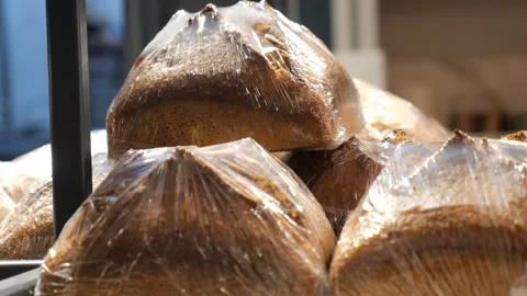 Fresh baked rye bread loaves wrapped in plastic film stacked on shelves in .. Stock Footage 332579467