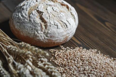 Fresh baked wheat bread loaf, a ghandful of wheat grain and wheat ears on a.. Stock Photos