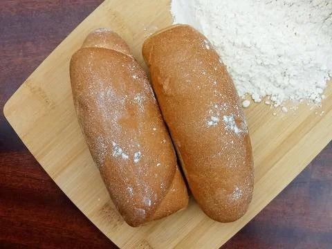 Fresh bakery bread rolls with flour on wooden board Stock Photos