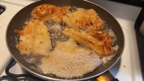 Fresh battered fish cooking in a bubbling frying pan Stock Footage 273176475