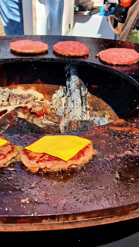 Fresh beef burger patties sizzling on round outdoor wood fire grill with me.. Stock Footage 337752964
