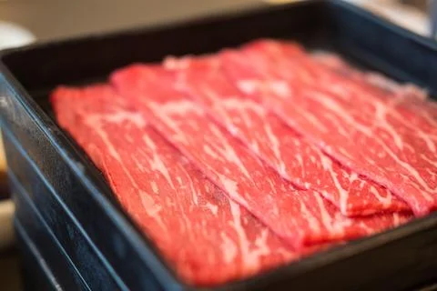 Fresh beef raw sliced with marbled texture served on black tray Stock Photos