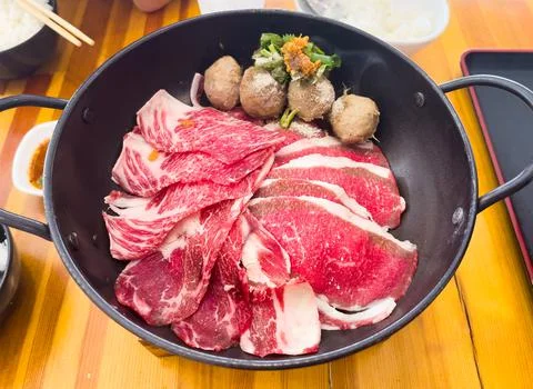 Fresh beef slice serving in the pan with meatball and some vegetable before f Stock Photos