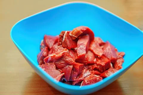 Fresh, bite-sized beef pieces rest in a vibrant blue bowl, symbolizing culi.. Stock Photos