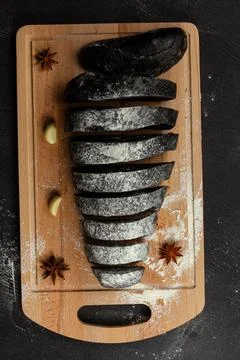 Fresh black rye bread on a cutting board on a black wooden table Stock Photos