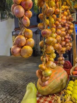 Fresh braided strings of yellow and red onions hanging outdoors at a vibran.. 库存照片
