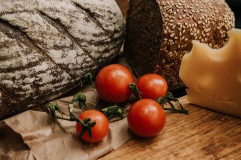 Fresh bread, cherry tomatoes, cheese on wooden black background Stock-Fotos