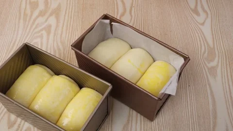 Fresh Bread Dough in Loaf Pans on Wooden Table Stock Footage 342120342