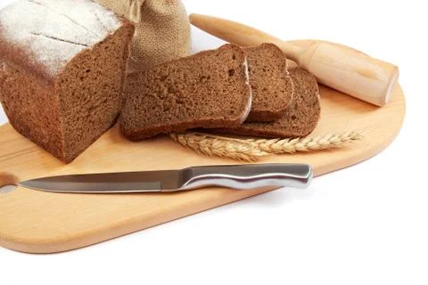 Fresh bread with ears and a knife of wheat on the wooden cutting board. Stock Photos