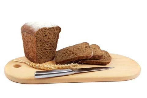 Fresh bread with ears and a knife of wheat on the wooden cutting board. Stock Photos