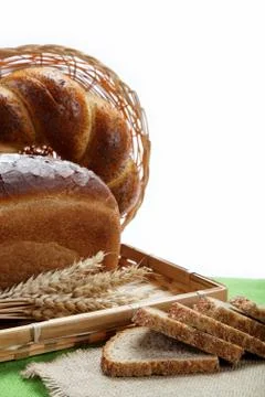 Fresh bread with ears of wheat on a green canvas. Stock Photos