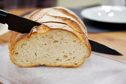 Fresh bread on the kitchen table and the sharp black knife Stock Photos