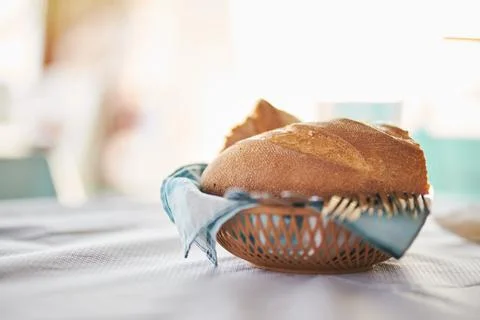 Fresh bread loaf in a small woven basket on a dining table Stock Photos