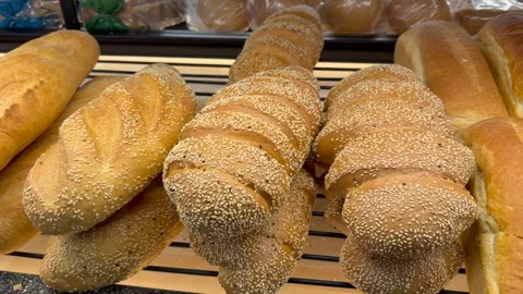 Fresh bread loaves with sesame topping displayed on bakery shelf. Bread looks Stock Footage 328352002