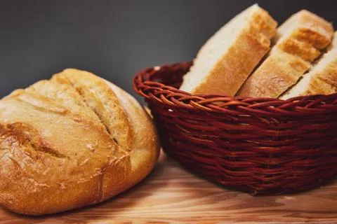 Fresh bread made from wheat flour in a wicker basket made of dark wood lies o Stock Photos