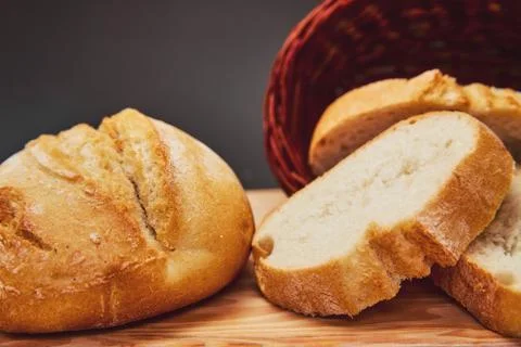 Fresh bread made from wheat flour in a wicker basket made of dark wood lies o Stock Photos