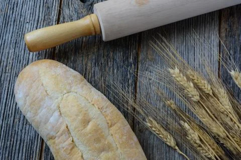 Fresh bread with a rolling pin and wheat on a rustic wood table Foto stock