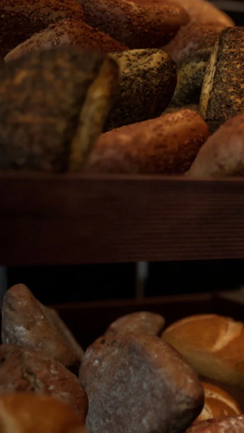 Fresh bread rolls and loaves stacked on wooden shelf in bakery Stock Footage 335098381