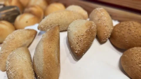 Fresh bread rolls and sliced baguettes arranged on a wooden tray Stock Footage 314707957