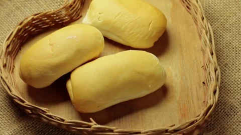 Fresh bread rolls being carefully placed in a rustic wicker basket Stock Footage 337210243