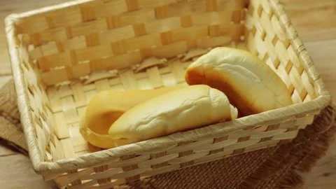 Fresh bread rolls being carefully placed in a rustic basket Stock Footage 337210250