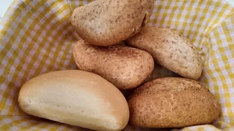 Fresh bread rolls being placed into a basket with yellow checkered cloth li.. Stock Footage 332144084