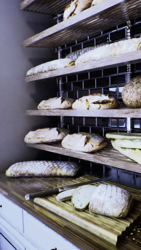 Fresh bread on shelves in a bakery with cutting board in view Stockbeeldmateriaal 336183089