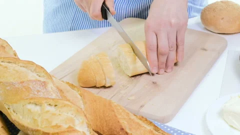 Fresh bread slice and cutting knife on rustic table. With wooman hands Stock Footage 88540628