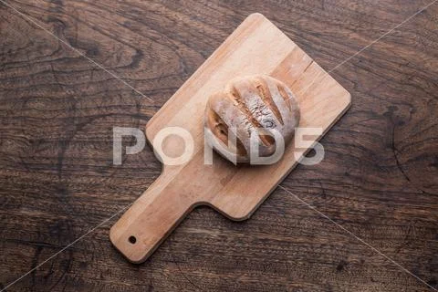 Fresh bread slice and cutting knife on rustic table Stock-Fotos