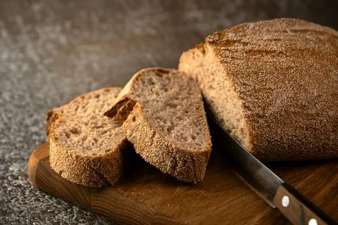 Fresh bread slice and cutting knife on cutting board Stock Photos