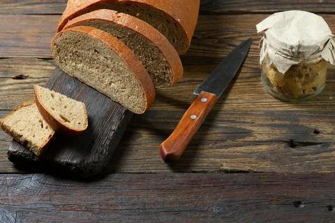 Fresh bread slice and cutting knife on rustic table Fotos Stock