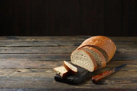 Fresh bread slice and cutting knife on rustic table 写真素材