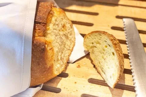 Fresh bread slice and cutting knife on rustic table Stock Photos