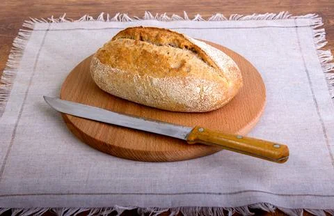 Fresh bread slice and cutting knife on table Stock Photos