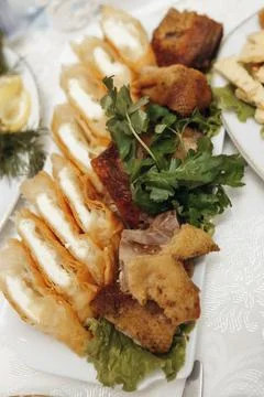 Fresh bread slices, crispy fried pieces, and greens on white plate Stockfoto's