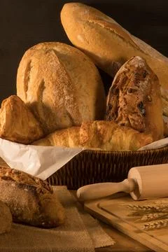 Fresh bread with wheat ears and bowl of flour on dark board, top view Stock Photos