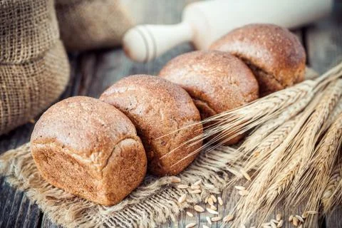 Fresh bread, wheat ears, sack of flour and rolling pin. Stock Photos