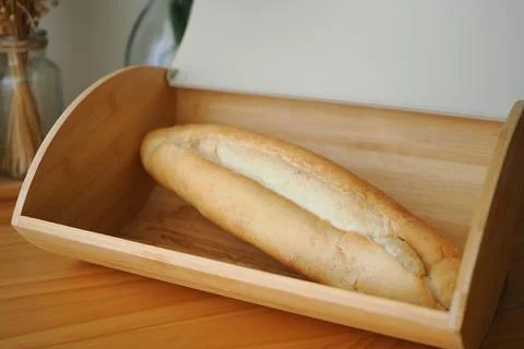 Fresh bread in a wooden bread box on a kitchen table Stock Photos