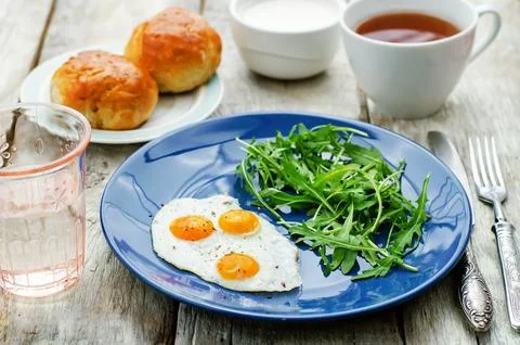 Fresh breakfast with scrambled eggs and arugula on a white wood background... Stock Photos