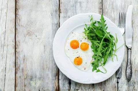 Fresh breakfast with scrambled eggs and arugula on a white wood background... Stock Photos