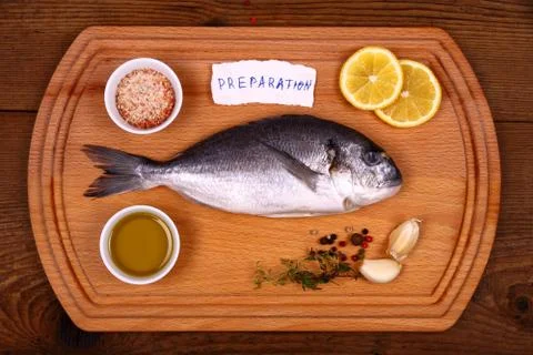 Fresh bream fish on cutting board with ingredients, pieces of paper Stock Photos