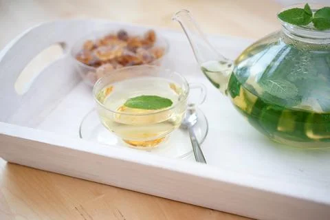 Fresh brewed mint tea on tray with teacup teapot and candi sugar healthy living Stock Photos