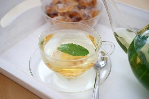 Fresh brewed mint tea on tray with teacup teapot and candi sugar healthy living Stock Photos