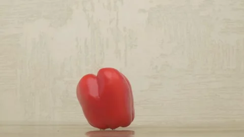 A Fresh, Bright Red Bell Pepper Resting on a Wooden Table Surface with Natural Video stock 284317549